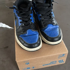 Nike Air Jordans svart/blå - Säljer ett par Nike Air Jordans i svart och blått skinn med klassisk design och vit platt sula. Skorna har snörning och rund tå, perfekt för dig som gillar streetwear och sneakers med ikonisk look.