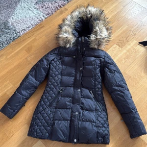 svart jacka - en fin svart jacka med päls luva och ett snyggt märke på ena armen