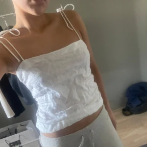 Vit linnetopp med knytband - Säljer en vit linnetopp med smala axelband som knyts upptill. Toppen är croppad och har en rak, enkel design som passar perfekt till sommaren. Strl M, men är liten i storleken 