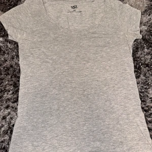 Grå basic t-shirt från 157 - En enkel och stilren grå t-shirt från 157 med rund halsringning och korta ärmar. Perfekt att matcha med jeans eller kjol för en avslappnad look. Tillverkad i mjuk bomull för extra komfort. Använd bara några fåtal gånger