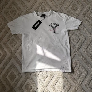 Vit t-shirt från Hoodrich med tryck - Vit t-shirt från Hoodrich med svart och rosa tryck både fram och bak. Trycket har texten 'From Nothing To Something' och en stor ängelgrafik. Klassisk passform och rund halsringning. Perfekt för dig som gillar streetwear.                                                          Hör av vid frågor✅⁉️.                                                 Skickas inom 24h✅⏳.                                                                Kvalité 👌✅