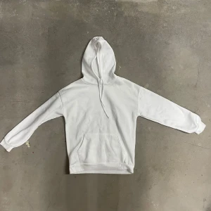 Vit hoodie från SHEIN - Säljer en klassisk vit hoodie från SHEIN i mjuk polyester. Tröjan har huva med dragsko och en stor magficka framtill. Perfekt för en chill och avslappnad stil.