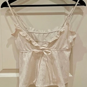 Kort top/linne med smala axelband med volang - Söt kort sommartopp med volangkant och knyt fram.