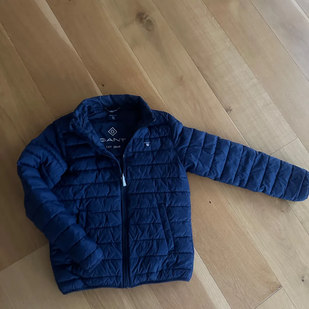 Snygg mörkblå jacka från Gant med quiltad design och dragkedja framtill den har två sidofickor och Gant-logga på vänstra bröstet en riktig stilig jag och har enkelt att matcha med olika outfits, speciellt mörkblå jeans 🤩. Takit.