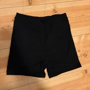 Svarta cykelshorts från Bik Bok - Svarta cykelshorts från Bik Bok i stretchigt material. De har en enkel och stilren design med normal passform och elastisk midja. Perfekta för sommaren eller träning.