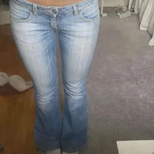 Blå bootcut jeans från Big Star - Säljer ett par klassiska blå jeans från Big Star med bootcut-passform. Jeansen har fem fickor, lågmidja och lätt slitna detaljer framtill. Perfekta för en avslappnad stil. Säljer då dom är försmå.             Midjemått: 34cm                                                          innerbenslängd: 70cm