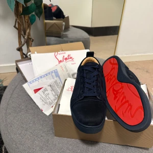 Mörkblåa sneakers från Christian Louboutin - Säljer ett par svarta sneakers från Christian Louboutin med klassisk röd sula och snörning. Skorna har en rund tå och är tillverkade i mocka med svarta detaljer. Perfekta för dig som vill sticka ut med exklusiv stil. ‼️Prutar redan ner varor innan jag lägger upp en anonnons så ingen skam bud ! ‼️ 