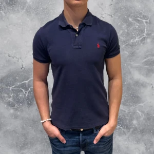 Ralph Lauren Piké Blå Slim-Fit - •Ralph Lauren Piké Blå. Skick: 8/10, Inga skador! (lite solblekt). Storlek: 14/16 år slim-fit = XS~. Modell: 173 cm, 65 kg. Sitter bra på modellen på bild! Authentic: ✅, QR Kod finns även i plagget. Hör av dig vid frågor eller funderingar, mvh Hessler’s;)