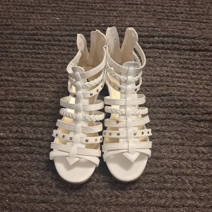 Vita sandaler med flätade remmar från Din Sko - Säljer ett par vita sandaler från Din Sko med flera flätade och släta remmar samt dragkedja bak. Skorna har öppen tå och platt sula, perfekta för varma dagar. Snygg och stilren design som passar till många outfits.