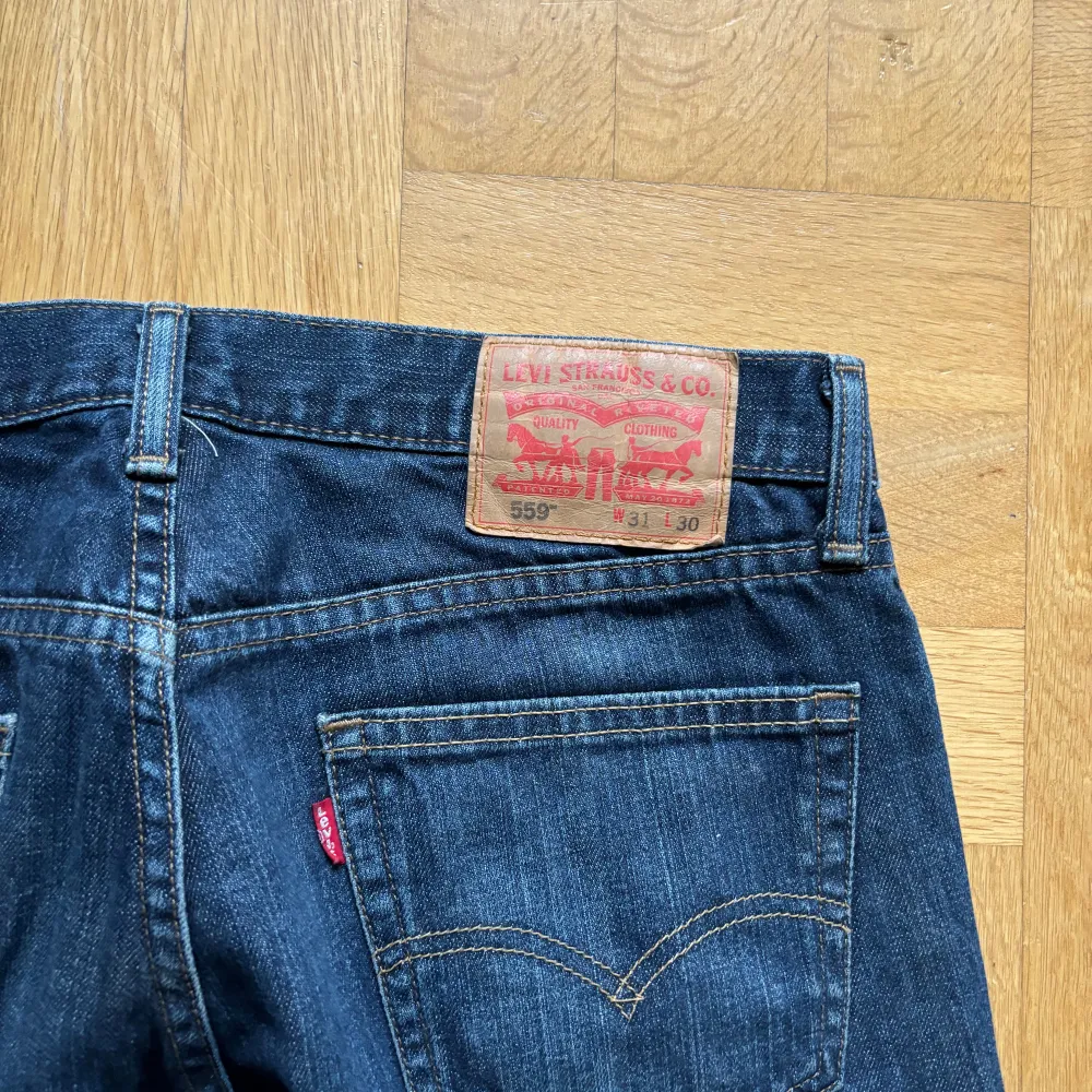 Säljer ett par klassiska blå Levi's 559 jeans med raka ben och normal passform. Längd: 104cm, midja: 42cm, leg opening: 21.5 cm. Jeansen har fem fickor, dragkedja och knapp i midjan samt tydliga Levi's-detaljer som röd etikett och läderpatch bak. Straight fit, flaired längst ner.. Farkut & Housut.