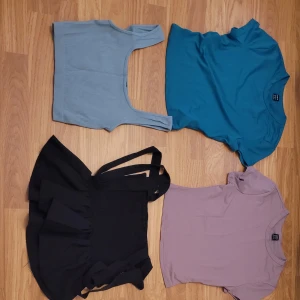 Mix av toppar i olika färger och stilar - Säljer ett paket med flera toppar i olika färger och modeller. Här finns bland annat en ribbad blå croppad topp, en blå t-shirt, en svart topp med volang och band, en lila t-shirt, en rosa croppad topp, en beige tubtopp, en grön ribbad topp med knyt, en grå sporttopp, en aprikos t-shirt, en mönstrad toppl och en rosa t-shirt. Allt i storlek xs.