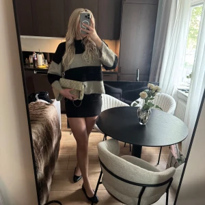 Randig stickad tröja i svart och beige - Säljer en stickad tröja med breda svarta och beige ränder. Tröjan har lång ärm, rund hals och en avslappnad passform. Perfekt för dig som gillar en enkel men snygg stil.