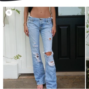 Ljusblå slitna bootcut jeans intressekoll - Säljer ett par ljusblå bootcut jeans med slitningar och hål på både fram- och baksida. Jeansen har klassisk femficksdesign och låg midja. Perfekta för en avslappnad och trendig look.