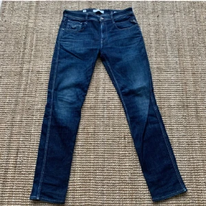 Replay jeans - Snygga mörkblå jeans från Replay med klassisk femficksdesign och raka ben. Byxorna har tydliga kontrastsömmar och läderpatch med Replay-logga bak i midjan. Perfekta för dig som gillar stilrena och tidlösa jeans.