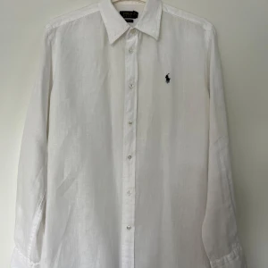 Skjorta i linne, Polo Ralph Lauren, M, vit - Vit skjorta från Polo Ralph Lauren med långa ärmar och knappar framtill. Storlek M. Skjortan har en broderad logotyp på bröstet. Relaxed fit. 100% linne. Skjortan är i mycket fint skick.   Mått: Längd ca 77 cm Byst ca 56 cm Midja ca 56 cm Ärmlängd mätt från axeln ca 60 cm Axelmått 42 cm