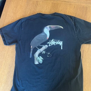 Stüssy t-shirt med tukantryck - Köpte tröjan på stüssy archive pop-up affären i Köpenhamn förra året. Storlek L.