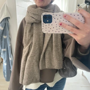 Sommar/vår jacka - Säljer en brun omlottjacka med dekorativa sömmar längs kanterna och knäppning framtill. Jackan har lång ärm och en avslappnad passform, perfekt för lager-på-lager. Materialet känns mjukt och bekvämt. Ginas ”Blanket jacket”. 