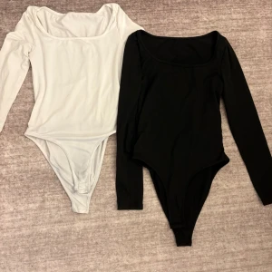 Svart och vit långärmad bodysuit - Två stilrena bodysuits i svart och vitt med lång ärm och rundad halsringning. Perfekta att styla till jeans eller kjol för en enkel och snygg look. Den vita är lite missfärgad från tvätten 💗