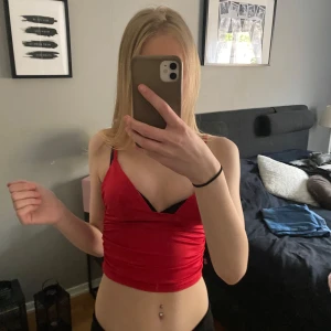 Röd croppad omlottopp - Säljer en röd croppad omlottopp med smala axelband. Toppen har en snygg v-ringning och är figurnära i modellen. Perfekt för dig som vill ha en trendig och stilren topp till sommaren.