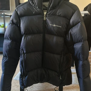 Mörkblå dunjacka från Sail Racing - Dunjacka strl M, dam. Använd 3 säsonger men fortfarande rätt fin. Lite förlust av stoppning i armvecken. 