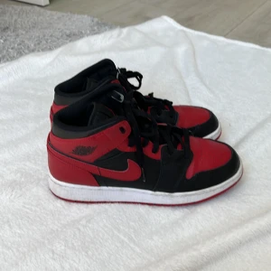 Nike Air Jordans i rött och svart - Säljer ett par klassiska Nike Air Jordans i rött och svart med vit sula. Skorna har snörning, rund tå och den ikoniska Air Jordan-loggan på sidan samt Jumpman-loggan på plösen. Perfekta för dig som gillar streetwear och sneakers med attityd.