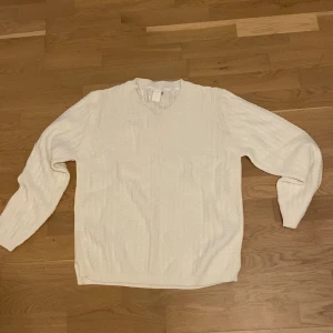 Vit stickad tröja från Åshild - Helt ny tröja Klassisk vit stickad tröja från Åshild i storlek 40/42. Tröjan har v-ringning och långa ärmar, perfekt för lager-på-lager under kyligare dagar. Enkel och stilren design som passar till mycket.