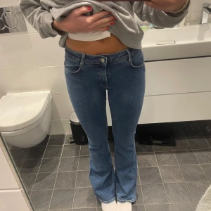 Blå bootcut jeans - Snygga blå bootcut jeans med klassisk femficksdesign och normal passform. Jeansen har en något utsvängd benslut och stängs med dragkedja och knapp. Perfekta för en avslappnad och trendig look.