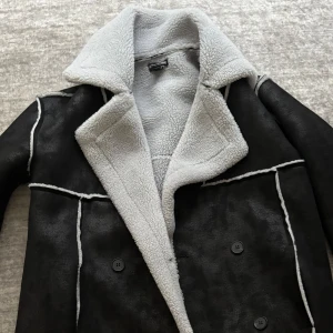 Vinterjacka från PrettyLittleThing - Säljer en snygg svart vinterjacka i fejkläder från PrettyLittleThing. Insidan är vit bomull, vilket gör den både varm och skön. Storlek 36. Köpt för 700 kr – säljes för 450 kr. Använd få gånger, i princip som ny!