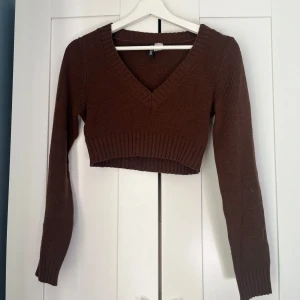 Brun croppad stickad tröja med v-ringning - Brun croppad stickad tröja med v-ring från H&M, storlek XS, inga skavanker, känns liten i storleken
