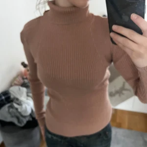 Polotröja  - Säljer en tight, ribbad polotröja i ljusrosa/ beige färg som är glittrig. Snygg fest topp passar även med lager. Skrov vid frågor! 🤗💗