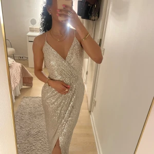 Glittrig långklänning med v-ringning - Säljer min balklänning som endast är använd 1 kväll. Det är en långklänning i silver med djup rygg samt har en slits vid benen. Perfekt skick, som ny! 👌🏽💕