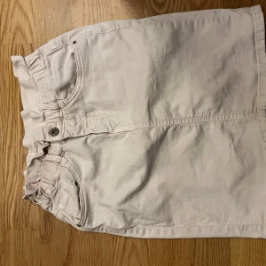 Ljusrosa jeanskjol med papperspåse-midja - Säljer en ljusrosa jeanskjol med papperspåse-midja och knappstängning framtill💗Kjolen har fickor både fram och bak samt en rak passform som slutar ovanför knäna. Perfekt för en fräsch och stilren look. 34 cm midjemått när kjolen är hyffsat utsträckt💗