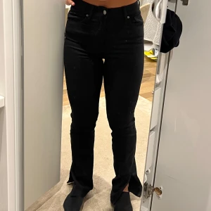 Svarta jeans med slits nertill - Säljer ett par svarta jeans med hög midja och slits vid bensluten från Gina Tricot i modellen "Molly". Byxorna har en öppning/slits nertill. Jeansen är knappt använda. 