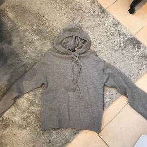 Grå hoodie från Gina Tricot - Mysig grå hoodie från Gina Tricot i storlek XS. Tröjan har huva med dragsko och ribbade muddar vid ärmslut och nederkant. Perfekt för en avslappnad stil.