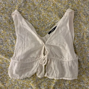 Vit croppad linnetopp från Bik Bok - Säljer en vit croppad linnetopp från Bik Bok med knytning framtill och djup v-ringning i storlek S 