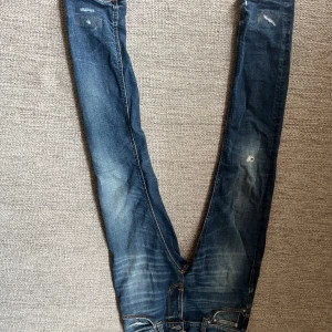 Nudie jeans med slitningar - Säljer ett par nudie jeans med slitningar och lagade detaljer. 30 i midjan och sitter bra i längden på mig som är 180