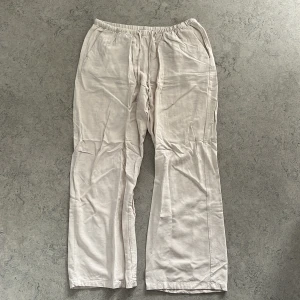 Beiga linnebyxor från Gina Tricot - Luftiga och sköna beiga linnebyxor från Gina Tricot med resår i midjan. Byxorna har raka ben och en avslappnad passform, perfekta för varma dagar. Tillverkade i ett mjukt linnematerial som ger en chill vibe. Lite kortare i benen efter att ha blivit tvättade.