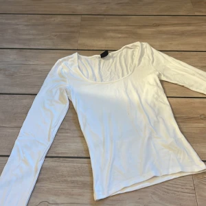 Vit långärmad topp från Gina Tricot - En basic vit långärmad topp från Gina Tricot i storlek XS. Modellen har en rundad, lite djupare urringning och är gjord i mjuk bomullsmix. Även en liten öppning längst nere. Den är i fint skick!