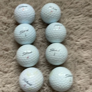En blandning av titleist bollar det är 8 bollar - Bilderna visar flera golfbollar av märket Titleist, inklusive modeller som Pro V1x, Velocity, AVX, Tour Soft, NXT och Tour Speed. Detta är inte en bok, utan sportutrustning för golf.