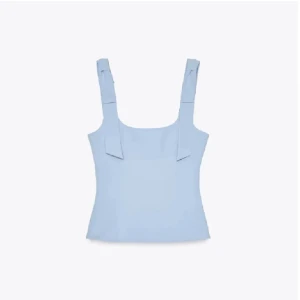 Ljusblå linnetopp med knytband - Supersöt ljusblå linnetopp med breda axelband och knytband på axlarna. Toppen har en rak, figurnära passform och är perfekt för varma dagar. Enkel och stilren design som är lätt att matcha med jeans eller kjol.