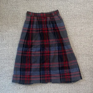 Rutig midikjol - rutig midikjol i tjockt material. snygg passform med plisserad framsida och slät baksida ❤️ dock mindre defekter som att knappen saknas vid dragkedjan och fållen börjar gå upp i nederkant, dock enkelt fixat med nål och tråd! ⭐️