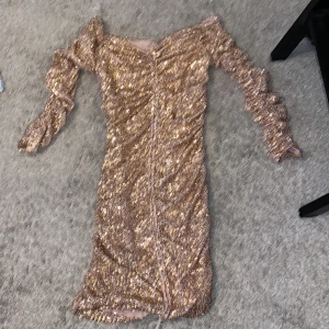 Glittrig guldklänning från Zara  - Superfin kort klänning från Zara i guld med massor av paljetter. Klänningen har långärmade ärmar, åtsittande passform och snygg rynkdetalj framtill. Perfekt för dig som vill sticka ut och glänsa! Materialet är syntet och känns lyxigt. Har endast använt den en gång den är helt fläckfri och säljer den på grund av att jag inte gillar guld men den är perfekt för fest tillfällen:) kan så klart skicka fler bilder på men var lite lat att ta 🥹🫶🏻