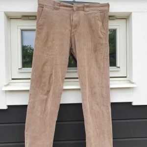 Broderade Manchesterbyxor - 🪡Beiga manchesterbyxor i storlek 32/32 handbroderade av mig. En liten röd blomma med gräs på vänster framben och en större röd blomma på höger bakficka. Lite slitna mellan benen man annars i bra skick.  📍Om du bor i Uppsala erbjuder jag upphämtning, skriv till mig så berättar jag mer.  🧺Går att maskintvätta men var försiktig!