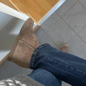 Beige mockaboots med dragkedja - Snygga boots i beige mocka med kilklack och dragkedja på sidan. Perfekta till jeans och ger en stilren look. Platt sula och rund tå gör dem bekväma för vardagsbruk.