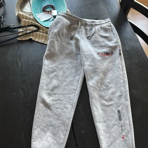 Grå mjukisbyxor från Hoodrich XS - Grå mjukisbyxor från Hoodrich i storlek XS. Byxorna har snörning i midjan, tryckt logga på benet och är tillverkade i mjukt bomullsmaterial. Perfekta för en chill och avslappnad stil.
