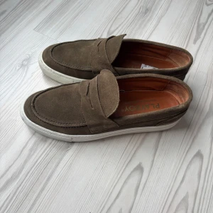 Loafers i mocka - Säljer ett par sparsamt använda loafers från Playboy i storlek 43, men de sitter mer som 44/44,5. Färgen är grön men ser mer ut som en blandning mellan grönt och mörkbrunt. De har lite smuts under men i stort sett inga synliga märken på sulan/skinnet