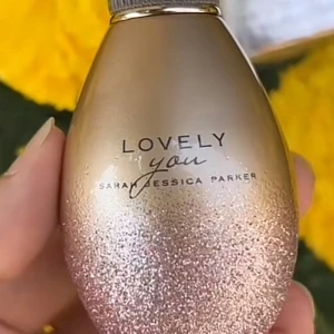 Lovely You parfym Sarah Jessica Parker - Parfymflaska Lovely You från Sarah Jessica Parker i en droppformad design. Flaskan är skimrande guld med rosa glitterdetaljer och har en elegant, räfflad transparent kork med gulddetaljer. Perfekt för dig som gillar lyxig och feminin stil.