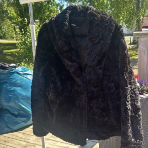 Svart pälsjacka från Zoul, stl 42 - Mysig svart pälsjacka från Zoul i storlek 42. Jackan har en fluffig och mjuk känsla med bred krage och helsvart foder. Perfekt för dig som vill ha en statementjacka med lyxig vibe och snygg siluett. Långärmad och passar till kalla dagar.