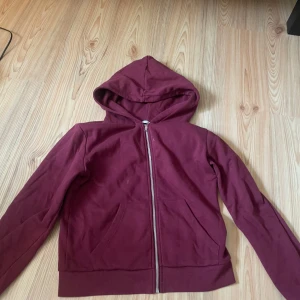 Vinröd hoodie med dragkedja - Vinröd hoodie från 157 i storlek M. Klassisk modell med huva, hel dragkedja och två fickor framtill. Tillverkad i mjuk bomullsmix, perfekt för lager-på-lager. Snygg och enkel stil som funkar året runt. Säljer även byxor till om man vill köpa ett sett💞