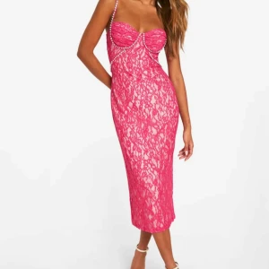 Rosa spetsklänning med pärldetaljer - Supersnygg rosa spetsklänning med smala axelband dekorerade med pärlor. Klänningen har slits bak och v-ringad byst med markerade kupor. Den är i storlek 8 (36) och är helt ny och oanvänd, nypriset låg på 600kr, jag säljer den för 250kr